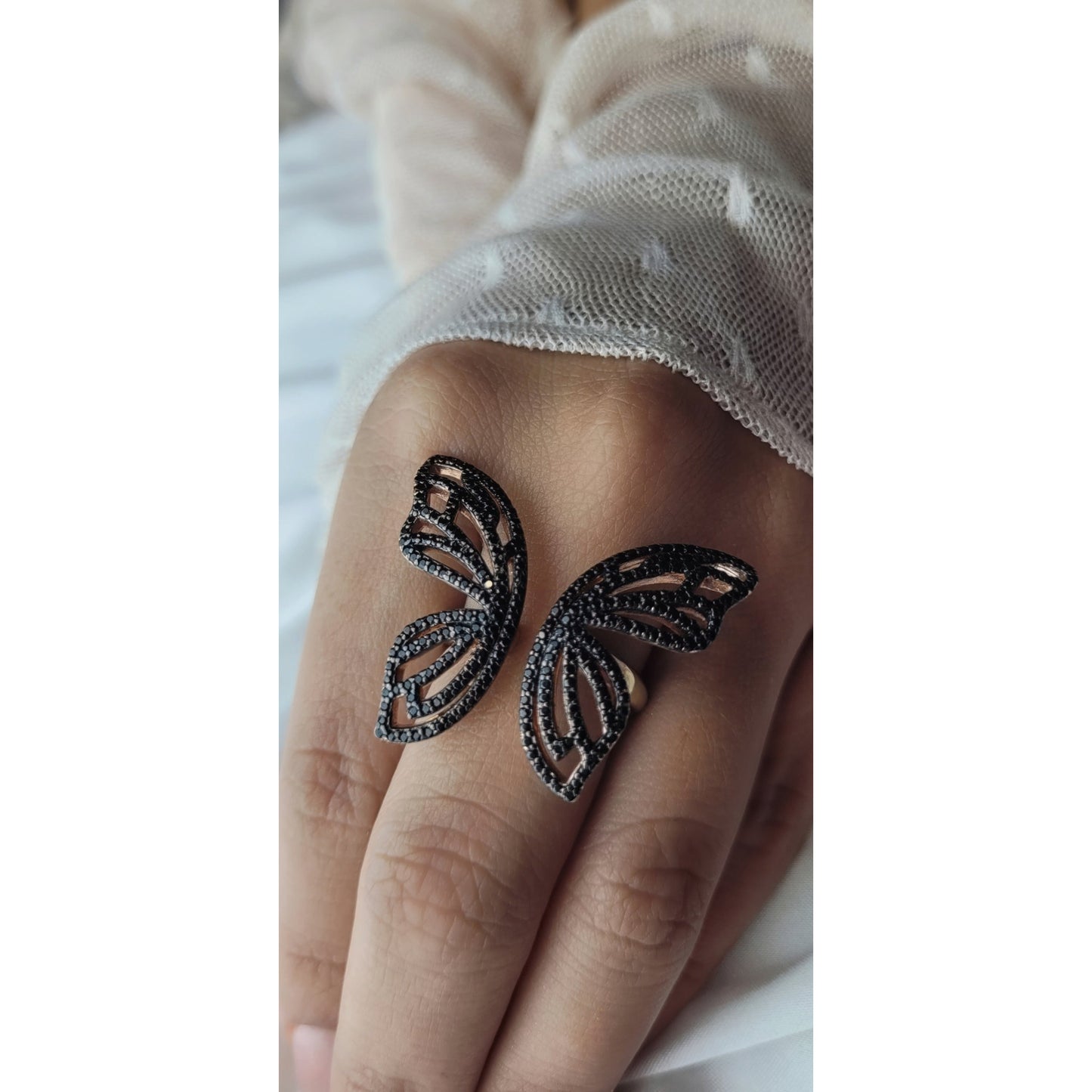 hand modeling open ring in the shape of a butterfly with black zirconia